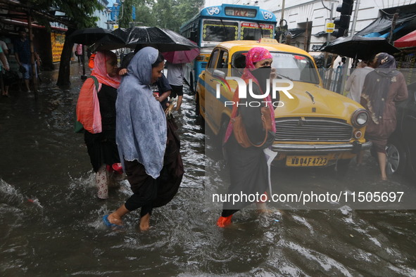 People walk on a flooded street during the heavy monsoon rain in Kolkata, India, on August 24, 2024. 