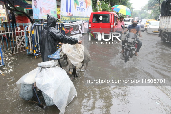 People walk on a flooded street during the heavy monsoon rain in Kolkata, India, on August 24, 2024. 