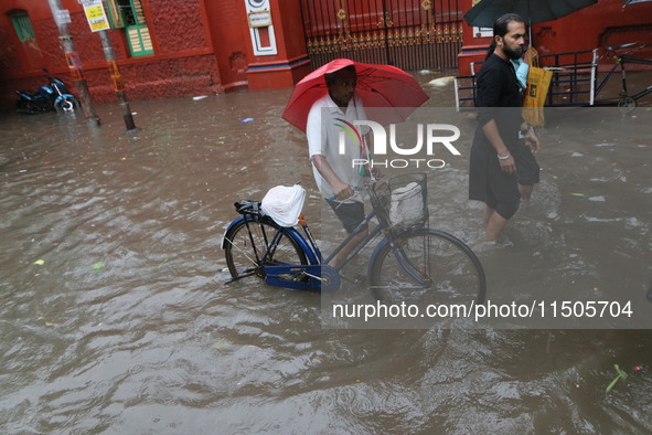 People walk on a flooded street during the heavy monsoon rain in Kolkata, India, on August 24, 2024. 