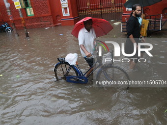 People walk on a flooded street during the heavy monsoon rain in Kolkata, India, on August 24, 2024. (