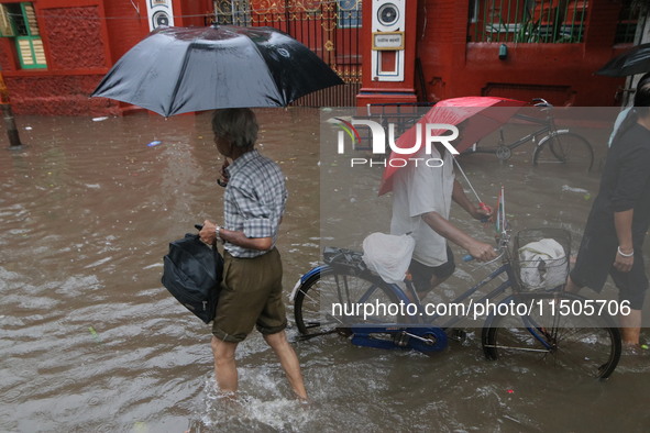 People walk on a flooded street during the heavy monsoon rain in Kolkata, India, on August 24, 2024. 