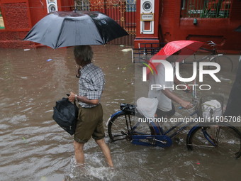 People walk on a flooded street during the heavy monsoon rain in Kolkata, India, on August 24, 2024. (