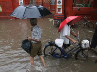 People walk on a flooded street during the heavy monsoon rain in Kolkata, India, on August 24, 2024. (