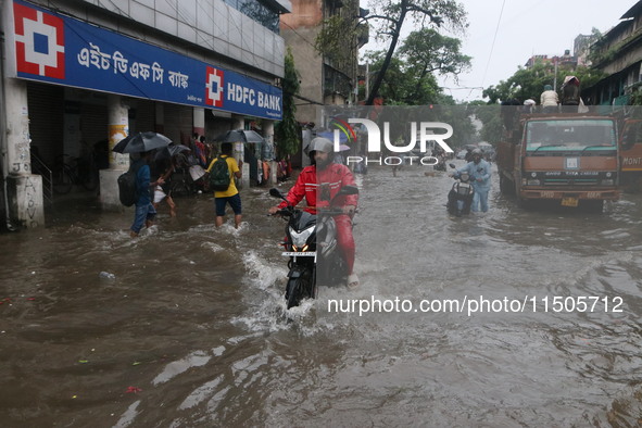 People walk on a flooded street during the heavy monsoon rain in Kolkata, India, on August 24, 2024. 