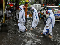 Sisters of the Missionaries of Charity make their way through a flooded street amidst heavy torrential downpour in Kolkata, India, on August...