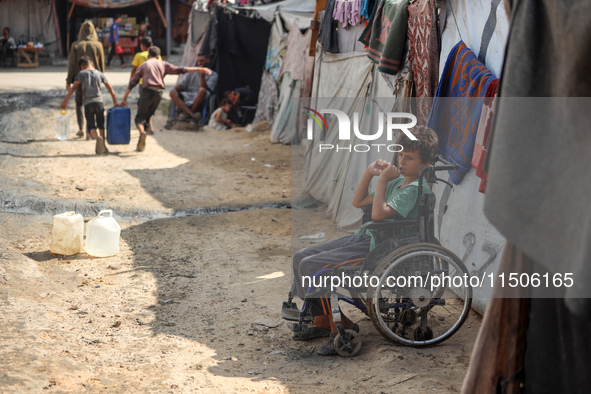 A displaced Palestinian boy sits outside his family's tent at a makeshift displacement camp in Deir el-Balah in the central Gaza Strip on Au...