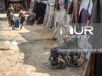 A displaced Palestinian boy sits outside his family's tent at a makeshift displacement camp in Deir el-Balah in the central Gaza Strip on Au...