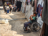 A displaced Palestinian boy sits outside his family's tent at a makeshift displacement camp in Deir el-Balah in the central Gaza Strip on Au...