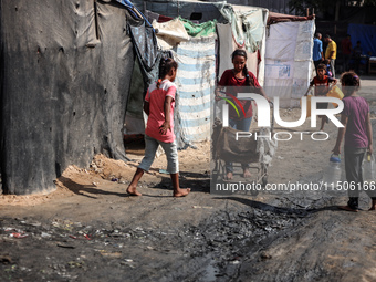 Displaced Palestinian children carry containers to fill with water at a makeshift displacement camp in Deir el-Balah in the central Gaza Str...