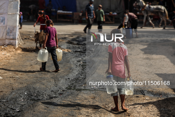 Displaced Palestinian children carry containers to fill with water at a makeshift displacement camp in Deir el-Balah in the central Gaza Str...