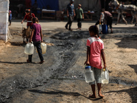 Displaced Palestinian children carry containers to fill with water at a makeshift displacement camp in Deir el-Balah in the central Gaza Str...