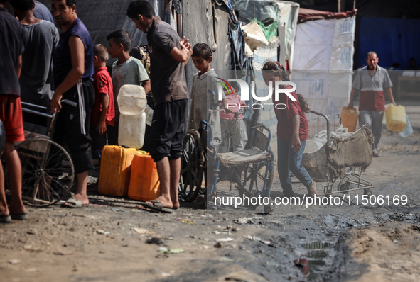 Displaced Palestinian children carry containers to fill with water at a makeshift displacement camp in Deir el-Balah in the central Gaza Str...