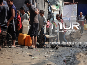 Displaced Palestinian children carry containers to fill with water at a makeshift displacement camp in Deir el-Balah in the central Gaza Str...