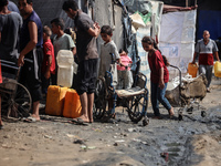 Displaced Palestinian children carry containers to fill with water at a makeshift displacement camp in Deir el-Balah in the central Gaza Str...