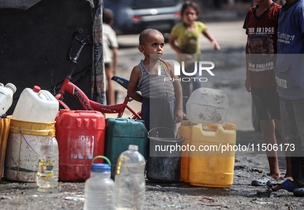 Displaced Palestinian children carry containers to fill with water at a makeshift displacement camp in Deir el-Balah in the central Gaza Str...