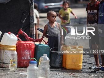 Displaced Palestinian children carry containers to fill with water at a makeshift displacement camp in Deir el-Balah in the central Gaza Str...