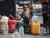 Displaced Palestinian children carry containers to fill with water at a makeshift displacement camp in Deir el-Balah in the central Gaza Str...