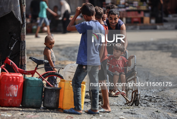 Displaced Palestinian children carry containers to fill with water at a makeshift displacement camp in Deir el-Balah in the central Gaza Str...