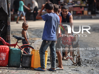 Displaced Palestinian children carry containers to fill with water at a makeshift displacement camp in Deir el-Balah in the central Gaza Str...