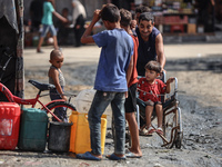 Displaced Palestinian children carry containers to fill with water at a makeshift displacement camp in Deir el-Balah in the central Gaza Str...