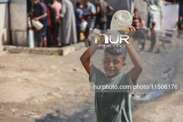 A displaced Palestinian child splashes water on his head during hot weather at a makeshift displacement camp in Deir el-Balah, Gaza Strip, o...