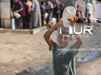 A displaced Palestinian child splashes water on his head during hot weather at a makeshift displacement camp in Deir el-Balah, Gaza Strip, o...