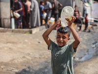 A displaced Palestinian child splashes water on his head during hot weather at a makeshift displacement camp in Deir el-Balah, Gaza Strip, o...