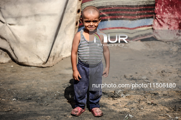 A displaced Palestinian boy stands outside his family's tent at a makeshift displacement camp in Deir el-Balah, Gaza Strip, on August 24, 20...