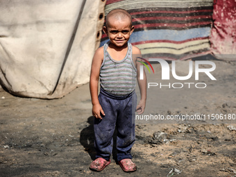 A displaced Palestinian boy stands outside his family's tent at a makeshift displacement camp in Deir el-Balah, Gaza Strip, on August 24, 20...