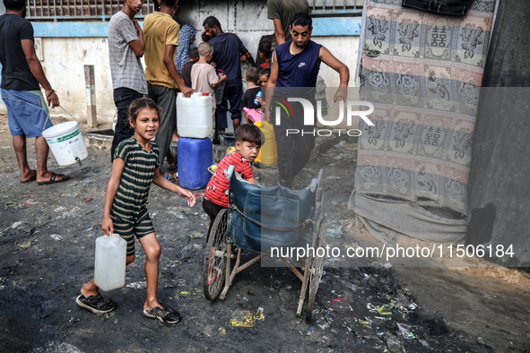 Displaced Palestinian children carry containers to fill with water at a makeshift displacement camp in Deir el-Balah in the central Gaza Str...