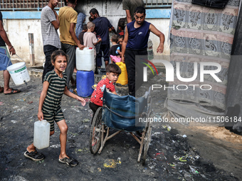 Displaced Palestinian children carry containers to fill with water at a makeshift displacement camp in Deir el-Balah in the central Gaza Str...