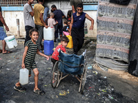 Displaced Palestinian children carry containers to fill with water at a makeshift displacement camp in Deir el-Balah in the central Gaza Str...