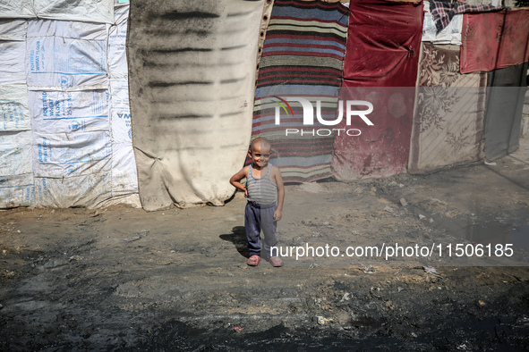 A displaced Palestinian boy stands outside his family's tent at a makeshift displacement camp in Deir el-Balah, Gaza Strip, on August 24, 20...