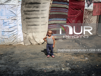 A displaced Palestinian boy stands outside his family's tent at a makeshift displacement camp in Deir el-Balah, Gaza Strip, on August 24, 20...