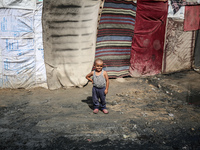 A displaced Palestinian boy stands outside his family's tent at a makeshift displacement camp in Deir el-Balah, Gaza Strip, on August 24, 20...