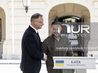 Ukrainian President Volodymyr Zelenskiy and Polish President Andrzej Duda embrace after a joint press conference with Lithuanian Prime Minis...