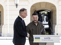 Ukrainian President Volodymyr Zelenskiy and Polish President Andrzej Duda embrace after a joint press conference with Lithuanian Prime Minis...