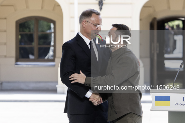 Ukrainian President Volodymyr Zelenskiy and Polish President Andrzej Duda embrace after a joint press conference with Lithuanian Prime Minis...