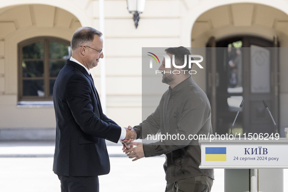 Ukrainian President Volodymyr Zelenskiy and Polish President Andrzej Duda shake hands after a joint press conference with Lithuanian Prime M...