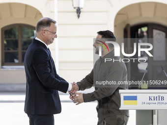 Ukrainian President Volodymyr Zelenskiy and Polish President Andrzej Duda shake hands after a joint press conference with Lithuanian Prime M...