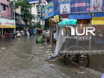 Rickshaw pullers wait for customers during a water-logged street after heavy monsoon rain in Kolkata, India, on August 24, 2024. (