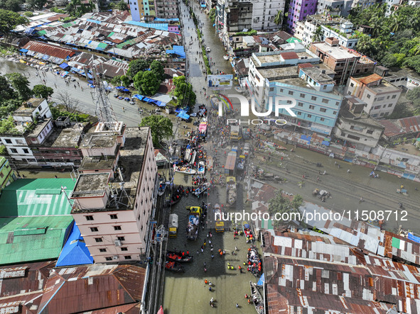 An aerial view shows volunteers transporting relief materials for flood-affected people in the Mohipal area of Feni district in Chittagong d...