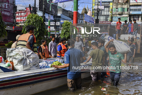 Volunteers wade through floodwaters to transport relief material for flood-affected people in Feni district in Chittagong division, Banglade...