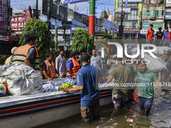 Volunteers wade through floodwaters to transport relief material for flood-affected people in Feni district in Chittagong division, Banglade...