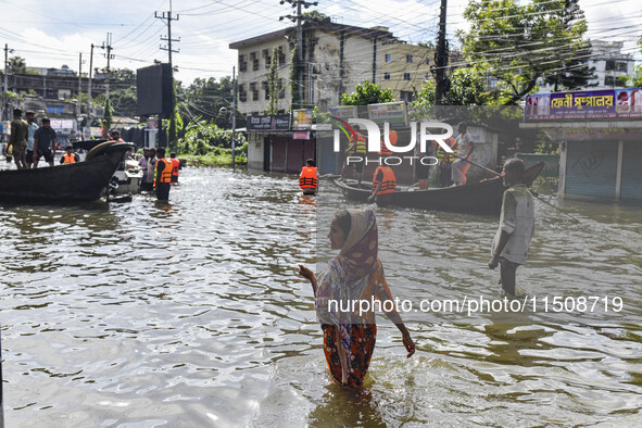 People wade through floodwaters in Feni district in Chittagong division, Bangladesh, on August 24, 2024. 