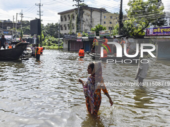 People wade through floodwaters in Feni district in Chittagong division, Bangladesh, on August 24, 2024. (