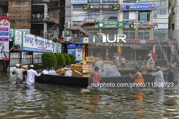 Volunteers wade through floodwaters to transport relief material for flood-affected people in Feni district in Chittagong division, Banglade...