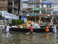 Volunteers wade through floodwaters to transport relief material for flood-affected people in Feni district in Chittagong division, Banglade...