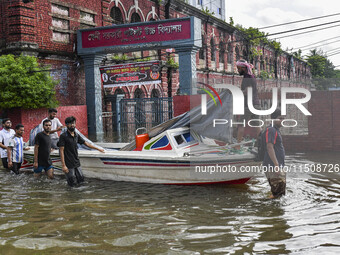 People wade through floodwaters in Feni district in Chittagong division, Bangladesh, on August 24, 2024. (