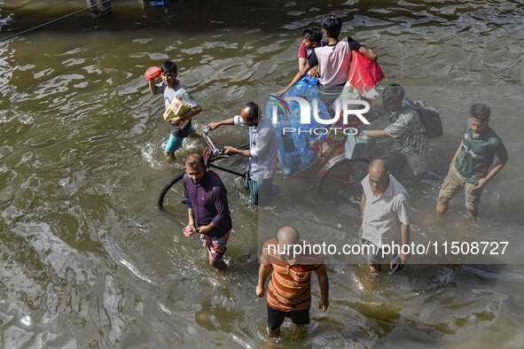 People wade through floodwaters in Feni district in Chittagong division, Bangladesh, on August 24, 2024. 